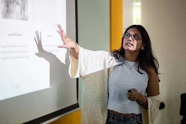 Teacher gestures toward projector slideshow